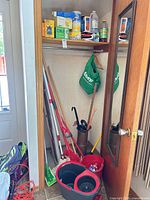 Overall view of closet with cleaning tools, buckets and umbrella stand