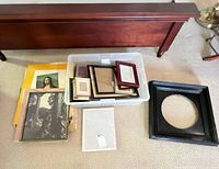 Lot overview showing tub of frames, loose large black frame, stack of prints