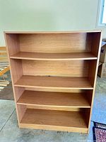 Front view of light cherry oak tone particleboard bookcase with four shelves