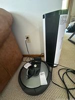 Roomba vacuum with charging dock and tower fan side-by-side
