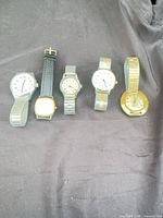 Five wristwatches lined up on fabric background