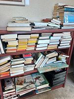 Three shelves densely filled with mixed hardcover and paperback books
