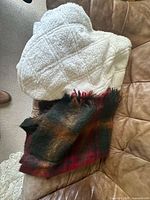 Stack of throw blankets showing cream sherpa and fuzzy plaid
