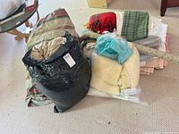 Full lot piled on floor showing multiple folded linens, throws, comforter in bag