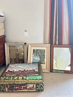 Group shot of two framed prints, framed mirror and decorative tin box
