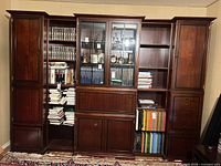 Front view of complete wall unit showing five sections with glass doors, cabinets, shelves and drawers