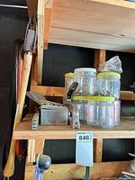 Shelf showing hatchet, bow saw, staple tacker and jars of fasteners