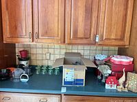 Overall countertop view of appliance, dessert bowls, tins, décor, and utensil box