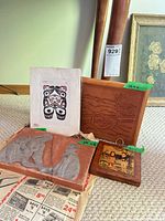 Group shot of four items: Dempsey Bob print, leather panel, terracotta plaque, wooden folk plaque
