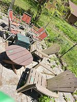 Group view showing Adirondack chairs, folding chairs, one green side table and round wood table