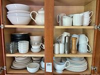 Open cupboard showing entire mixed dinnerware collection