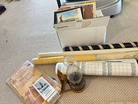 Overview showing box of booklets, rolled charts and hurricane lamp