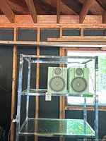 Overall view of chrome/glass shelving unit with speakers placed on middle shelf