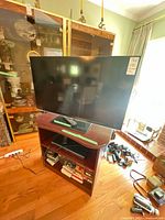 Full view of Panasonic TV on wood stand with Blu-ray player, remote and media visible
