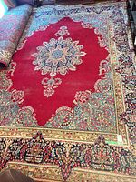 Full view of rug showing red field, medallion, borders, partial roll