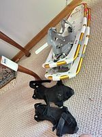 Snowshoes stacked with bindings visible alongside black attachments