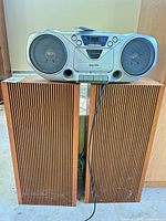 Boombox sitting on top of wood veneer speakers