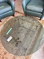 Round smoked glass coffee table between two chairs