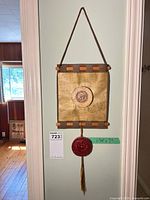 Full view of hanging plaque showing leather backing, parchment panel, top strap, wood dowels, red seal and tassel, scale tape