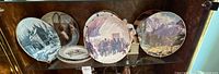 Shelf with four large decorative plates and stack of smaller plates