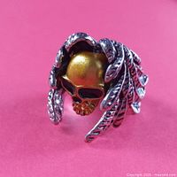 Front view of gold skull ring with feather hair design