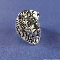 front view of detailed silver lion head ring on blue background