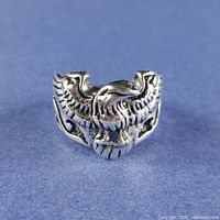 front view of silver-plated ring showing detailed bird with spread wings