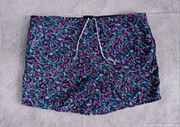 Front view of neon abstract Surf Odyssey swim trunks laid flat