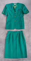 Full view of teal blazer and matching skirt laid flat