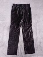 Full front view of black leather pants laid flat