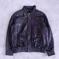 Full front view of black leather bomber jacket laid flat