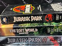 Stacked view of VHS and DVD spines showing titles and logos