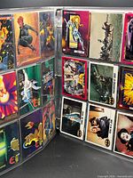 Binder open showing multiple pages of assorted cards including Batman, Superman and other franchises