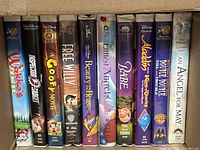 Row of ten VHS tapes inside box showing titles and case types