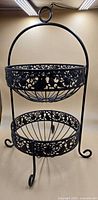 Full view of two-tier wrought iron basket stand showing overall form