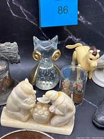Front view showing glass owl, horse figurine, bone animal grouping, miniature barrels, part of bell