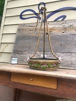 Full view of hanging lamp on table showing overall form, chain and supports