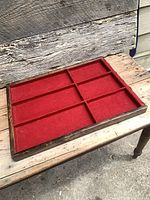 Full view of wooden display tray showing six red felt compartments