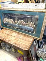 Full framed artwork resting on table, shows size and frame