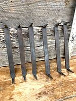 All six iron staples aligned alongside ruler showing 11 in. length