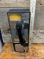 Full view of payphone with handset and ruler for scale