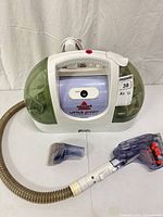 Front view of Bissell Little Green cleaner with hose, TurboBrush and small nozzle displayed
