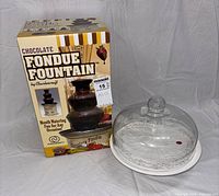 Boxed Charlescraft chocolate fondue fountain beside glass cake dome on pedestal