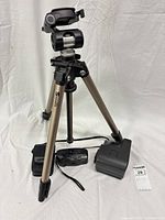 Tripod standing with camera, Polaroid accessory and case around base