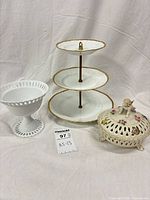 Front view of all three items: tiered stand, milk glass compote, cherub trinket box