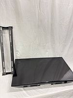 Front view of Samsung TV with screen facing up beside wall-mount bracket