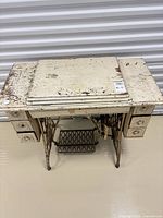 Top view of closed white distressed cabinet with six drawers and treadle base