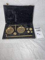 Open case displaying balance beam, pans, weights and key