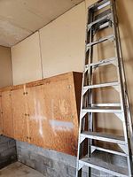 Full view of aluminum A-frame ladder leaning against wall