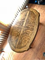 Top view showing oval shape and burl veneer pattern under protective glass
